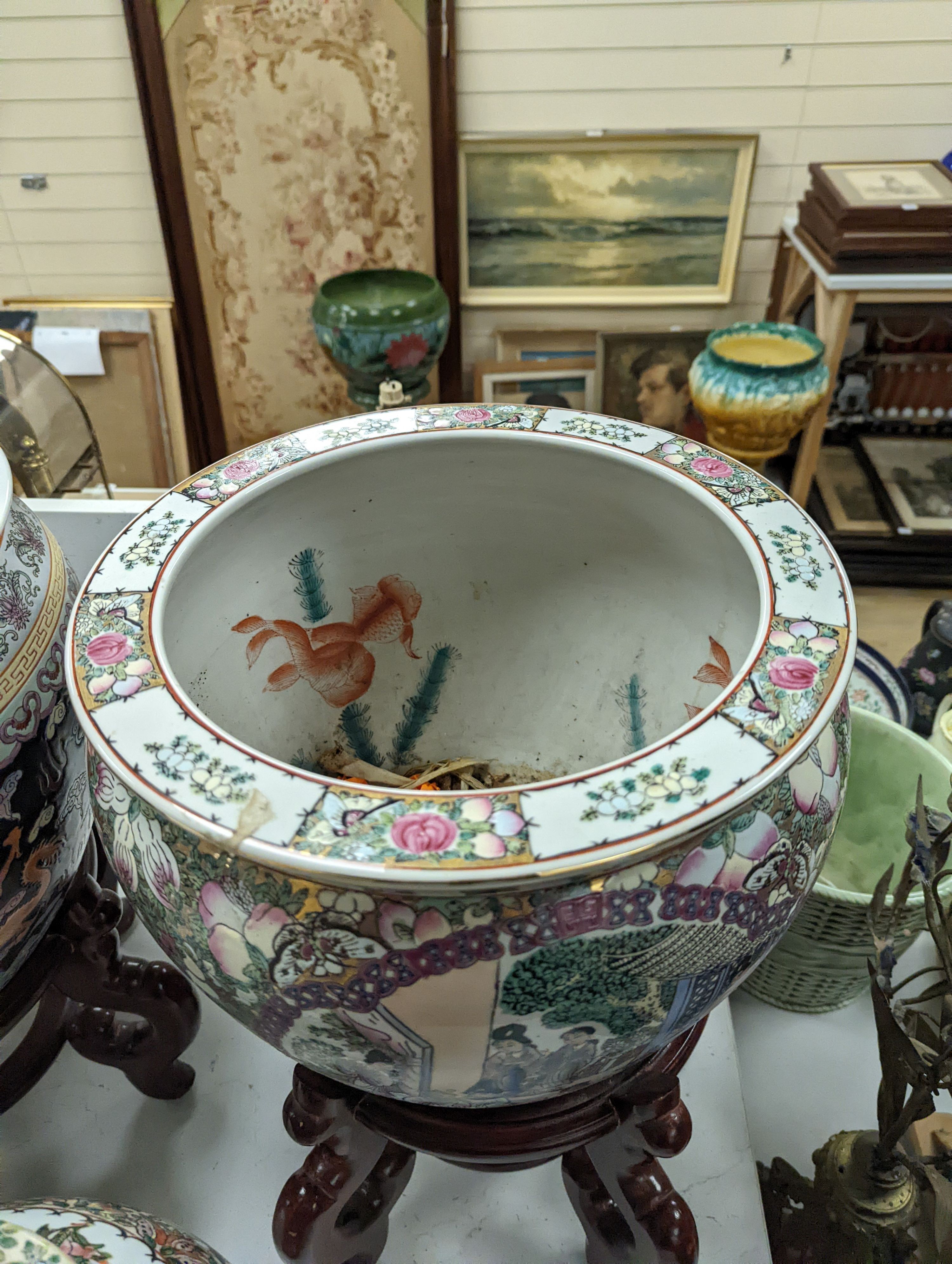 A pair of Chinese fish bowls on hardwood stands and a similar jar and cover, Fish bowls and stands 54 cms high.